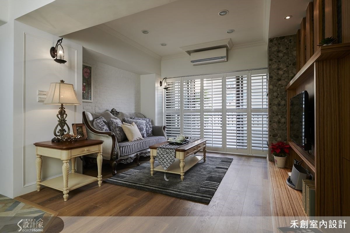 改造後的客廳以木百葉代替一般的落地窗簾，配合酒窖式的儲藏櫃及電視牆，充滿厚實的歐式鄉村風味道；而拿掉玻璃拉門後，格局豁然開朗，即使上方做了夾層，也沒有壓迫感
