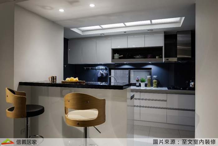 廚具上櫃設計了木作層板，除了使櫃體看起來更活潑，也讓一些難以收納的鍋子找到合適位置。利用吧檯區隔廚房與餐廳的空間，同時也來一些生活情趣，整體配色採單色系，運用深淺變化使視覺不單調、完美提升開放式廚房的質感。